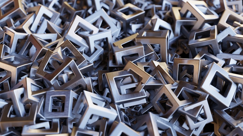 Pile of metallic square spiral frames stacked in a dense abstract pattern.