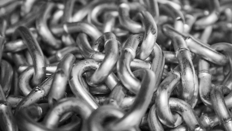Close-up of interlinked metal chains filling the frame in monochrome.