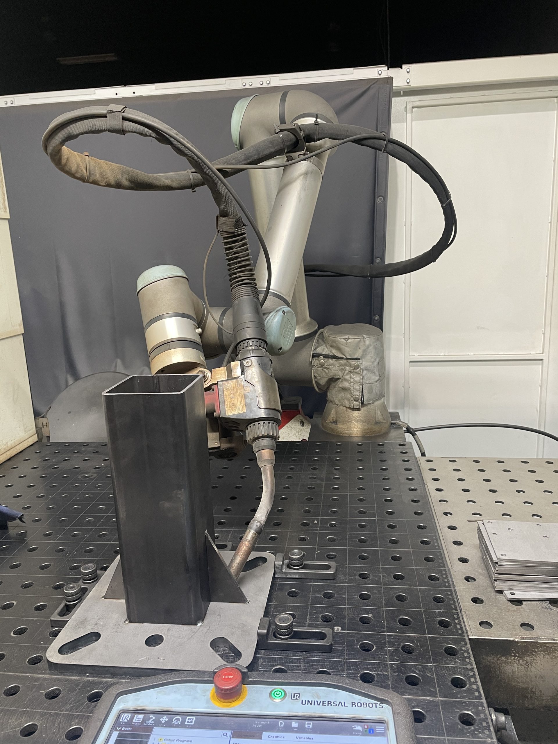 Industrial robotic welding arm over a metal worktable in a workshop.