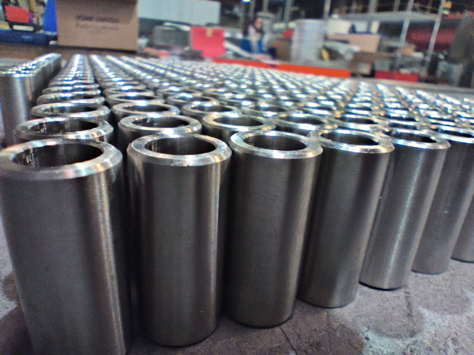 Rows of shiny metal cylinders arranged on a factory floor.