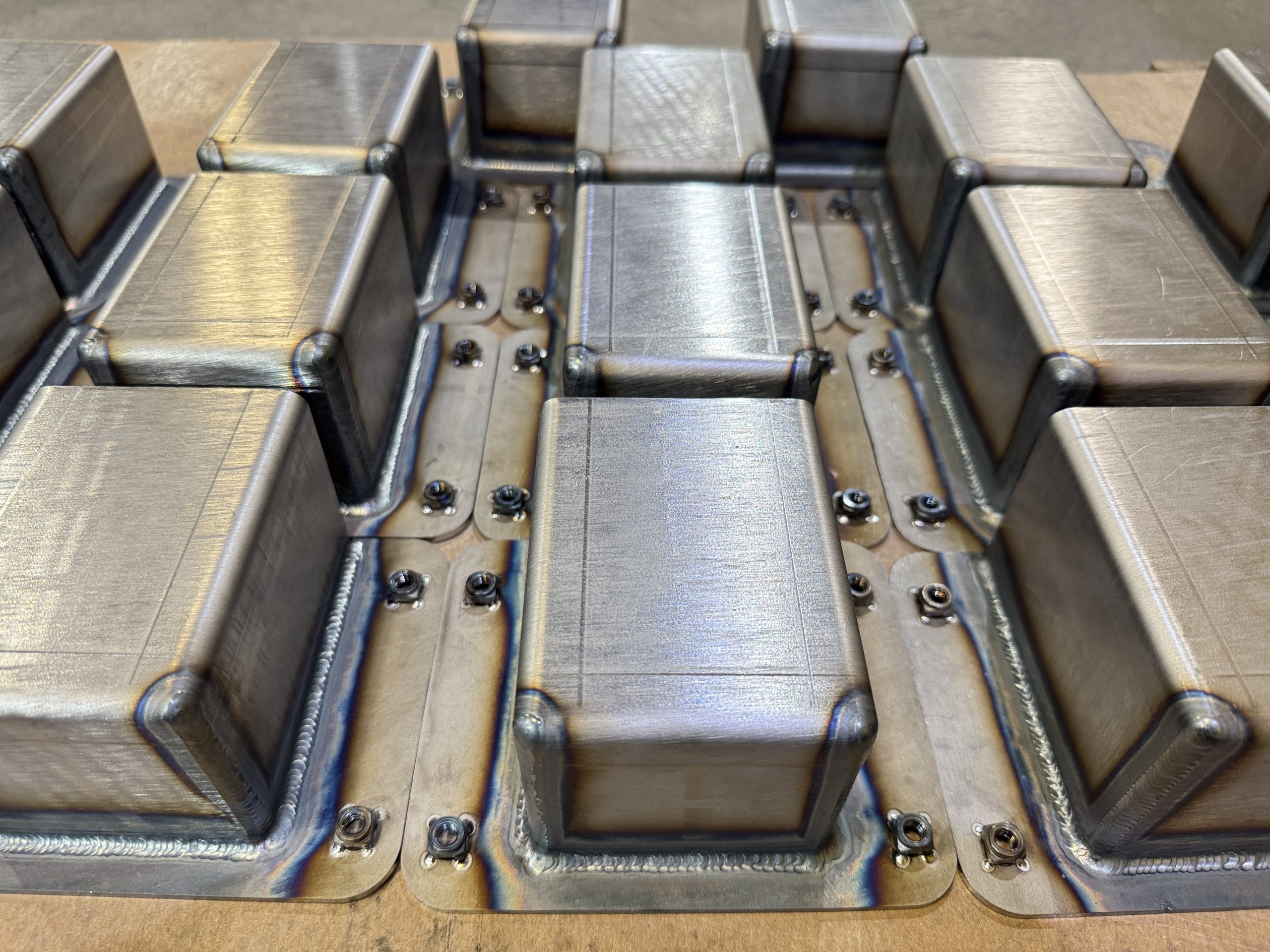Metal machined components arranged in rows on a workshop fixture.